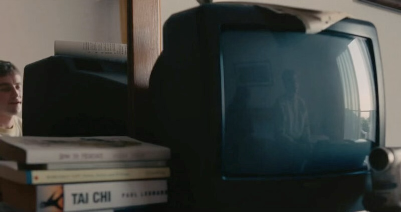 on an old tv's screen, a mirror image of a man and a girl sitting in a hotel room